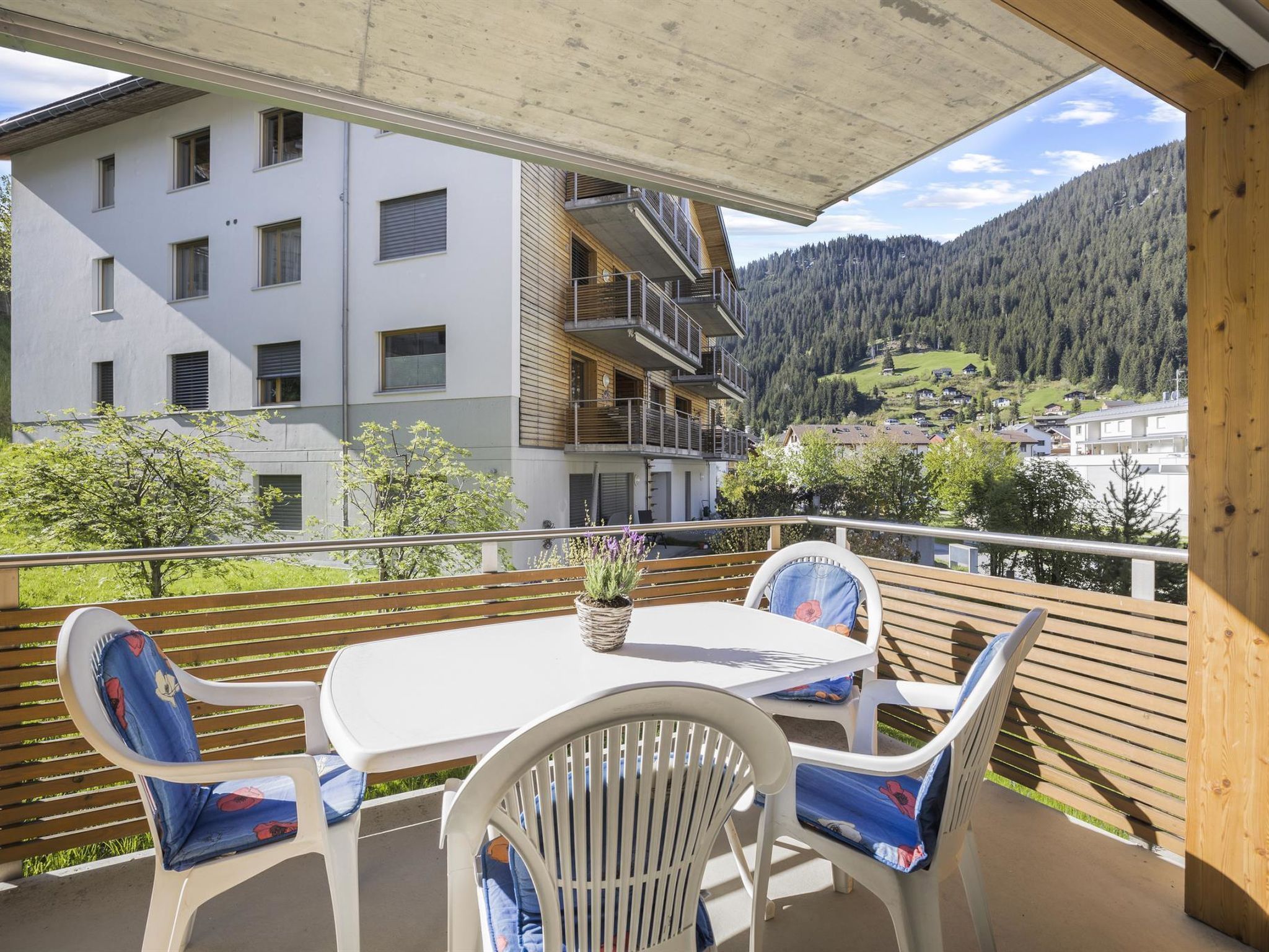 Un balcon avec une table et des chaises, donnant sur un paysage montagneux.