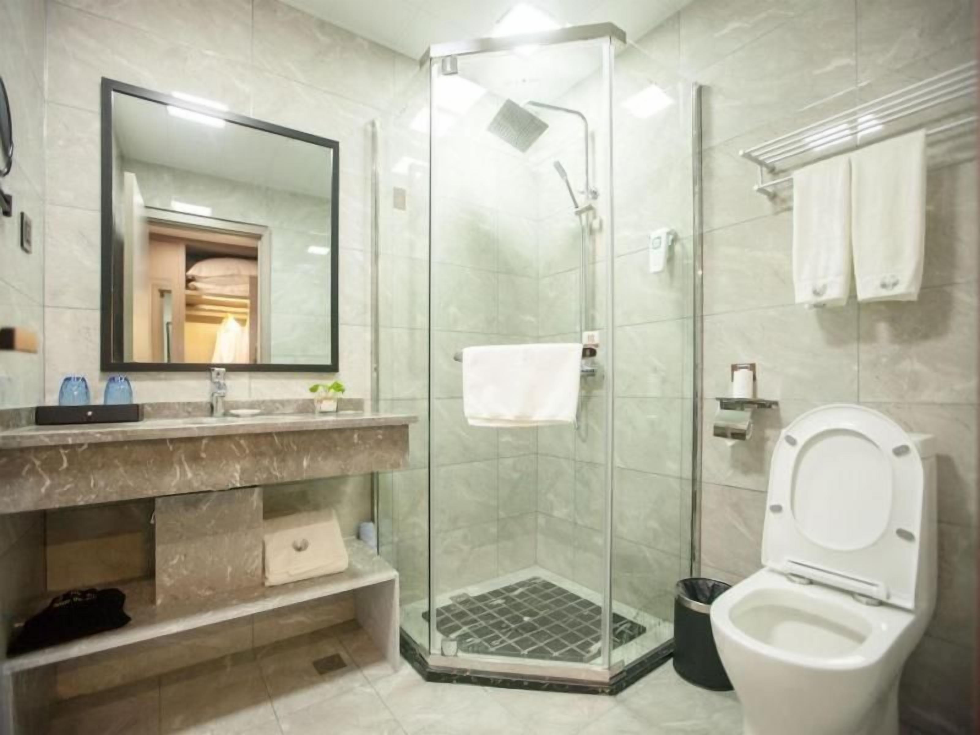 Ein modernes Badezimmer mit einer gläsernen Dusche, einer weißen Toilette und einem мраморном Waschtisch.
