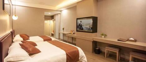 Habitación de hotel con dos camas, un escritorio, un televisor y una pequeña zona de estar.