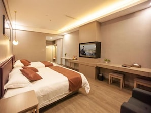 Quarto de hotel com duas camas, uma escrivaninha, televisão e um pequeno espaço de estar.