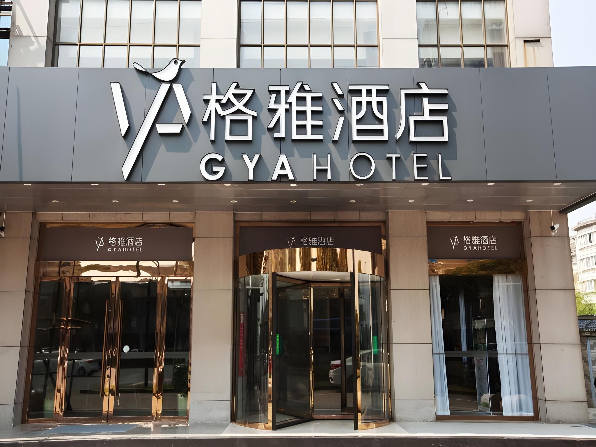 The exterior of GYA HOTEL with a modern facade, large glass entrance doors, and a bird logo above the name.