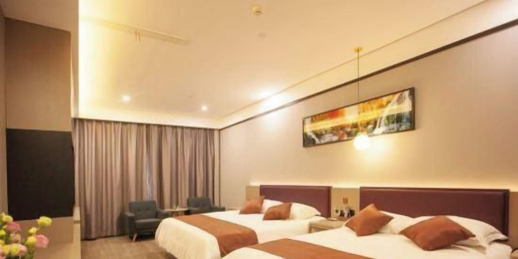 A hotel room with two beds, a desk, a chair, and a large painting on the wall.