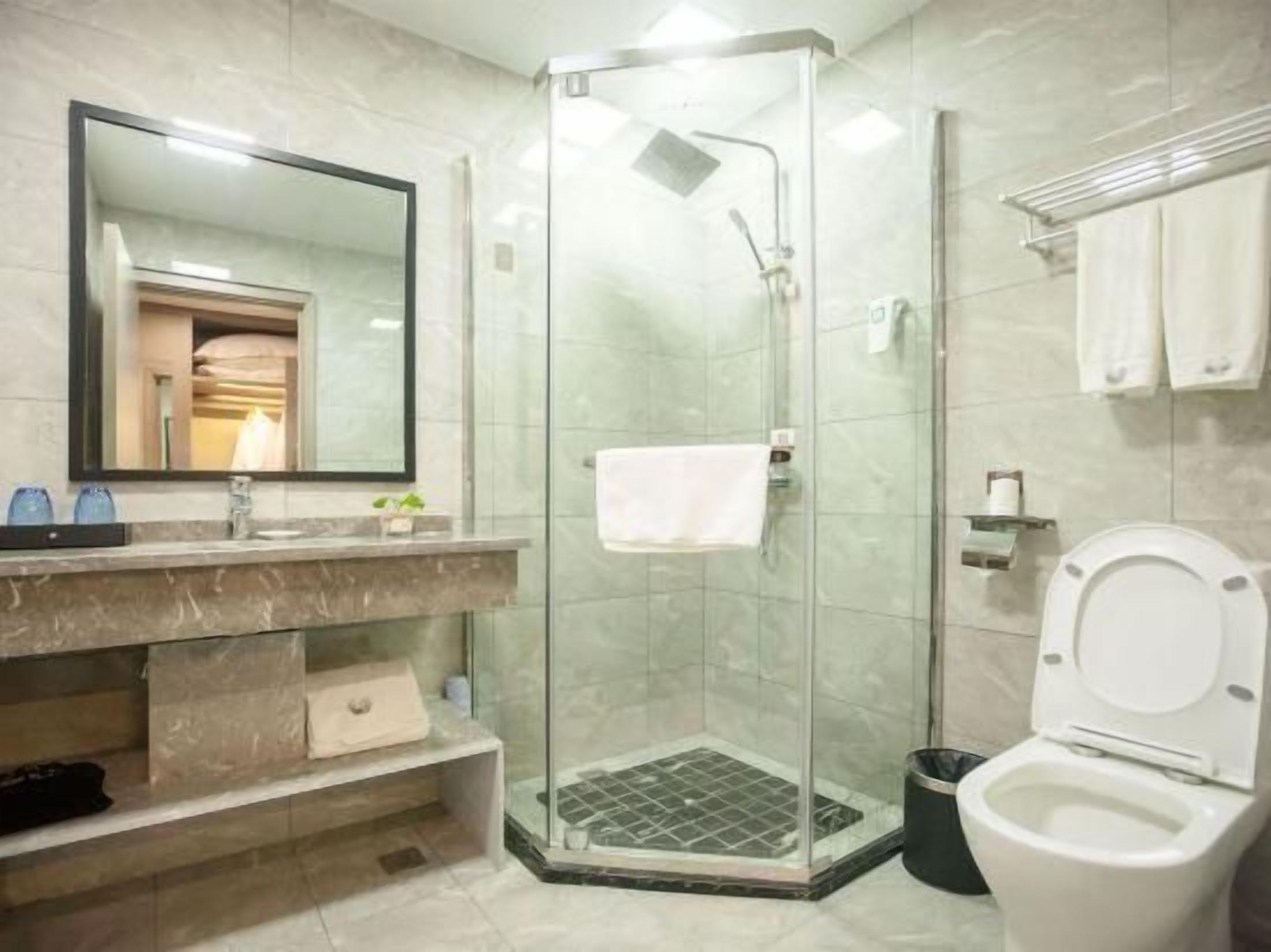 A modern bathroom with a glass-enclosed shower, a toilet, a sink with a mirror, and a towel rack.