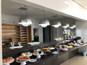 En buffé med ett urval av olika maträtter och ett vinställ i bakgrunden.