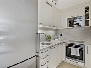 A modern kitchen with white cabinetry, stainless steel appliances, and a built-in oven. - Nr.58 Haus Ladina Appartement/Fewo,   Nr.58 Haus Ladina IH by Interhome (Lenzerheide)