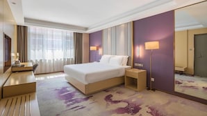 Una habitación de hotel con una cama grande, mesitas de noche, un escritorio y un espejo.