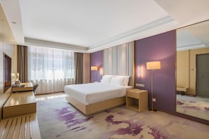 A hotel room with a large bed, bedside tables, a desk, a chair, a lamp, and a mirror. - Lavande Hotel (Tianjin)