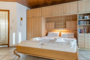 Ein Schlafzimmer mit einem hölzernen Bettgestell, einem Nachttisch, einem Kleiderschrank und einem Bücherregal.