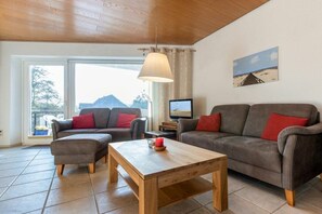 Ein Wohnzimmer mit zwei Sofas, einem Holztisch und einem Fernseher.