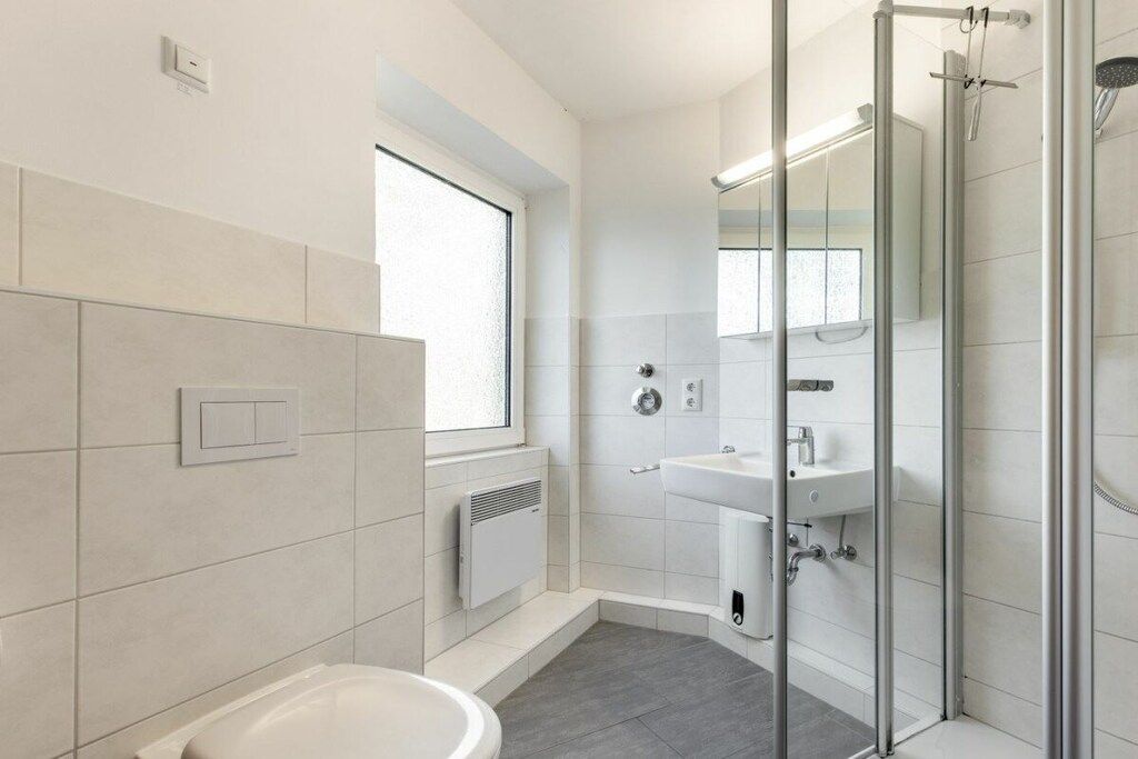 A modern bathroom with a toilet, sink, and glass shower enclosure.