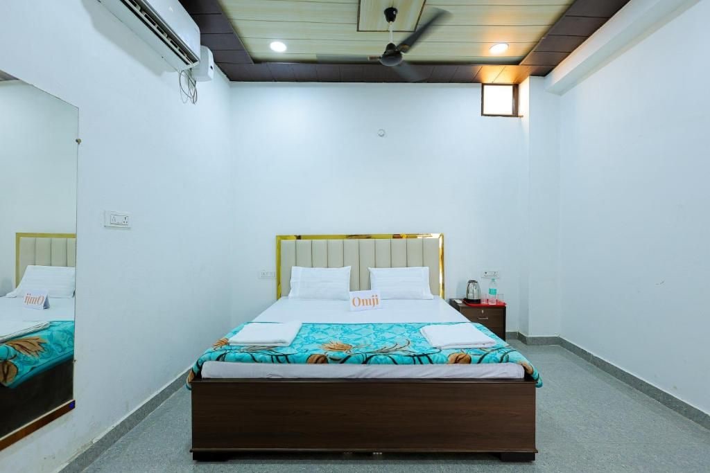 A hotel room with a bed, bedside table, and a mirror.