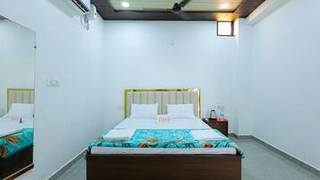 A hotel room with a bed, bedside table, and a mirror.