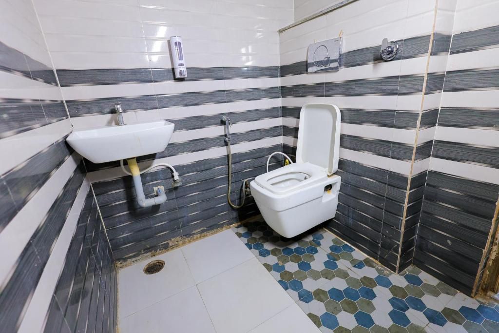 Un baño con inodoro, lavamanos y suelo de baldosas.