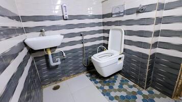 Un baño con inodoro, lavamanos y suelo de baldosas.