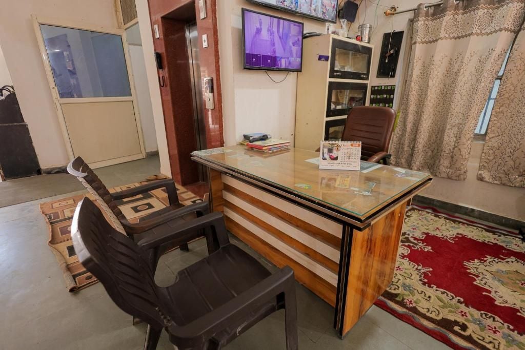 A room with a wooden desk, a television mounted on the wall, and a patterned rug.