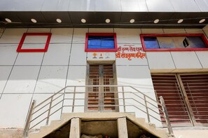 Un edificio con una escalera que lleva a una puerta, una ventana con marco rojo y un letrero con texto.