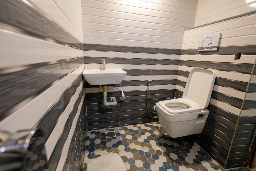 A bathroom with a white sink, toilet, and a tiled floor with a geometric pattern.