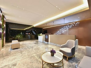 A modern lobby with a reception desk, seating area, and a decorative wall feature. - Lavande Hotel (Kunming)