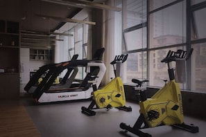 Un gimnasio con bicicletas estáticas y equipo de ejercicio, amplias ventanas y un diseño interior moderno.