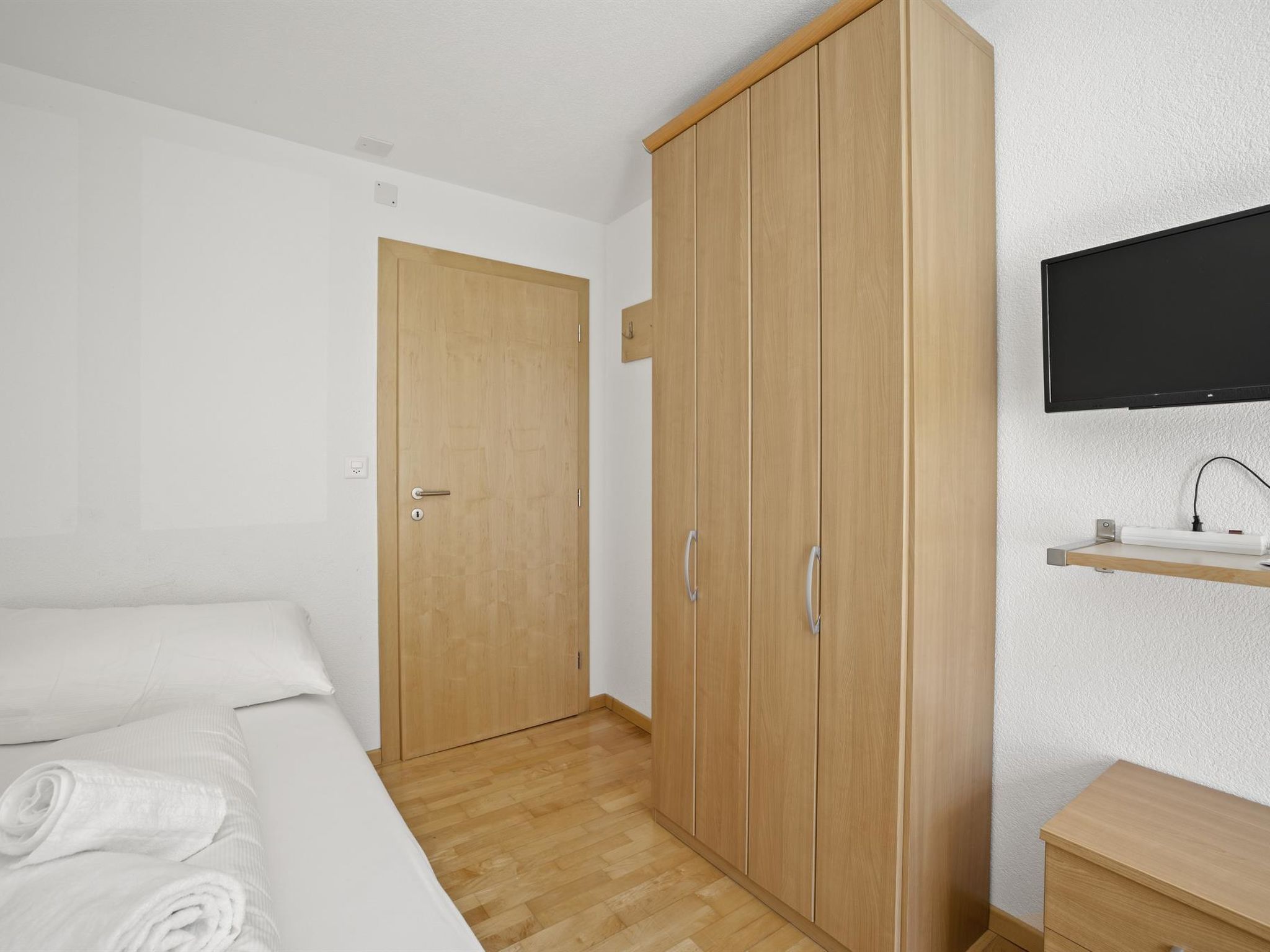 Une chambre à coucher comprenant un lit, une armoire, un téléviseur et une petite table de chevet.