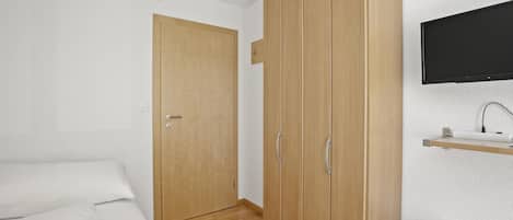 Une chambre à coucher comprenant un lit, une armoire, un téléviseur et une petite table de chevet.