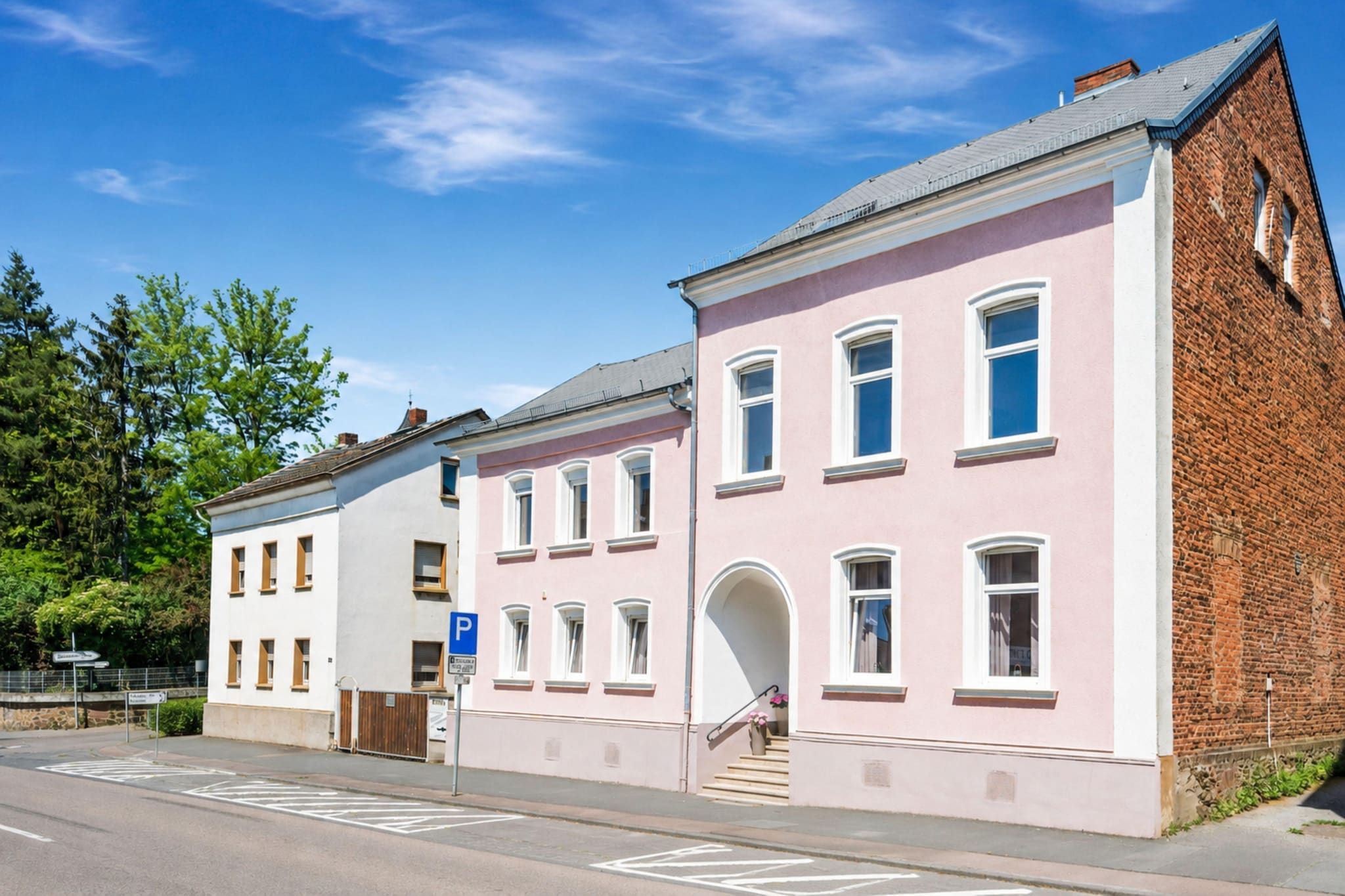 Ein zweistöckiges Gebäude mit einer rosafarbenen Fassade und einem Ziegelbruch auf der rechten Seite.
