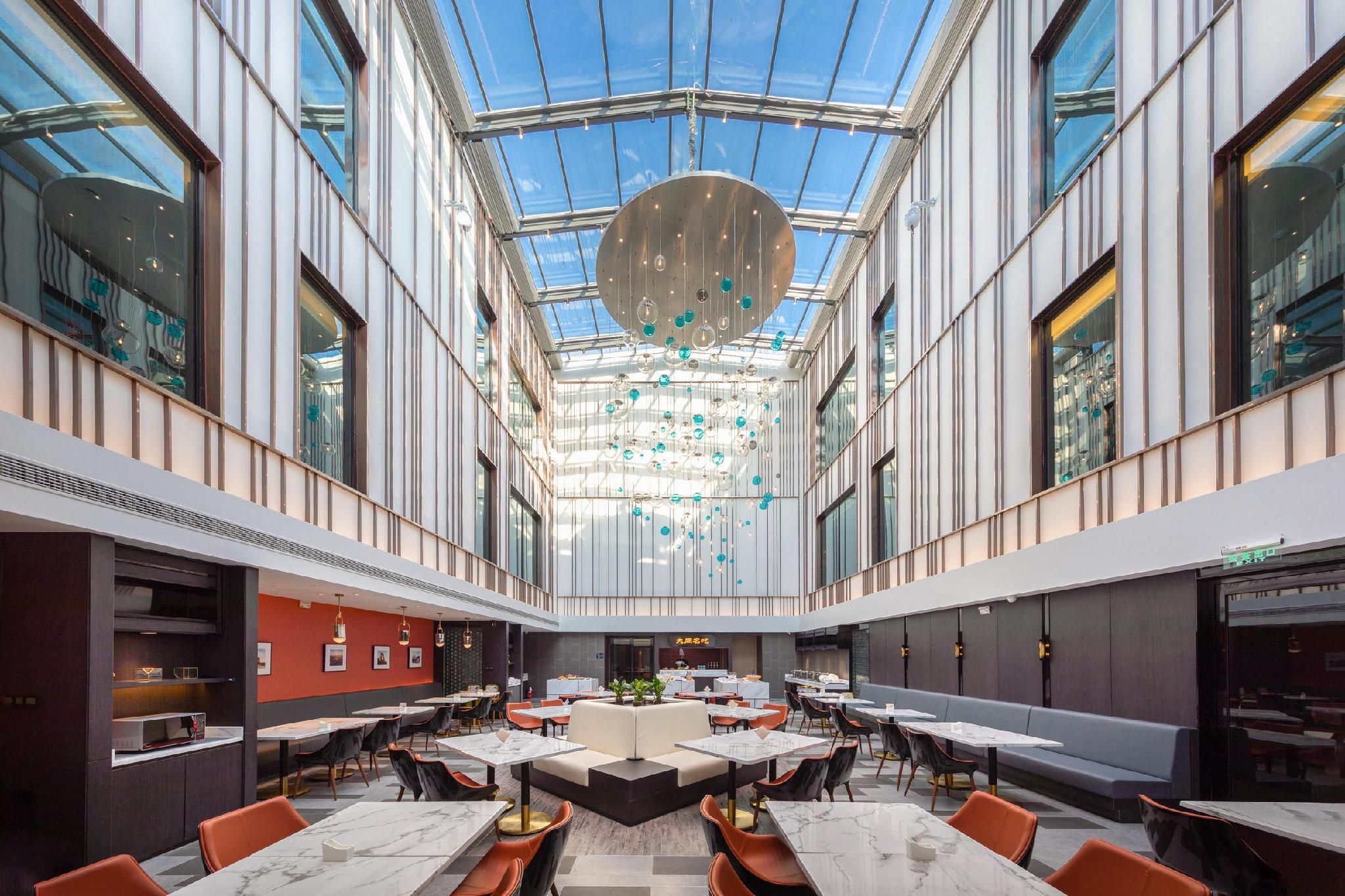 A spacious indoor dining area with high ceilings and a central chandelier.