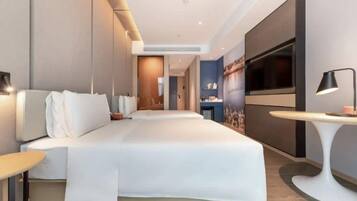 A modern hotel room with a large bed, a flat-screen TV, a desk, and a seating area.