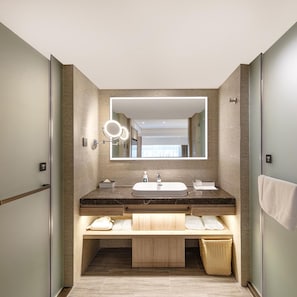 A modern bathroom with a large mirror, a sink, and a vanity with storage.