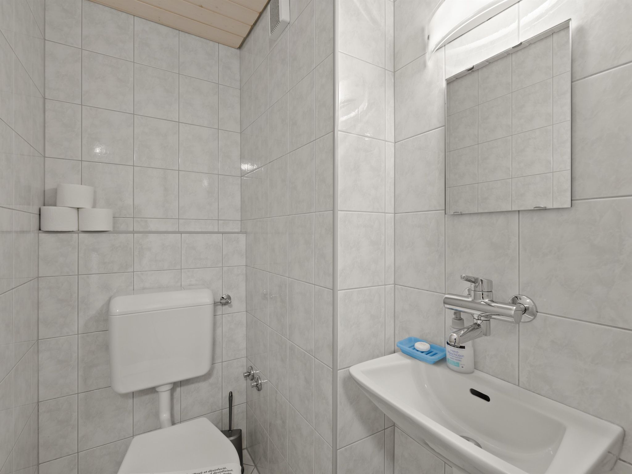 Ein modernes Badezimmer mit Toilette, Waschbecken und Spiegel.