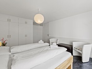 Une chambre moderne comprenant un lit, deux tables de chevet, une chaise et une armoire.