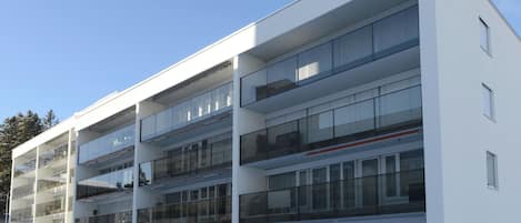 A multi-story building with balconies, large windows, and a flat roof.