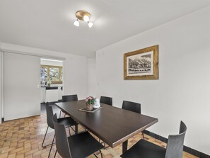 A dining area with a long table, chairs, and a framed picture on the wall. - Bellavista 6 Appartement/Fewo, Bad, WC, 3 Schlafräume by Interhome (Parpan)