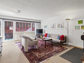 A living room with a sofa, a chair, a coffee table, a TV, and a floor lamp. - Lang Appartement/Fewo,   Ferienwohnung Lang IH by Interhome (Churwalden)