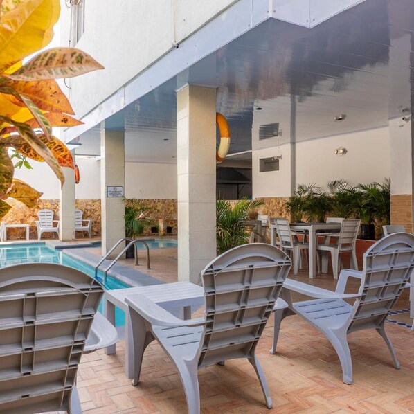 Zona junto a la piscina con sillas de descanso, una piscina y mobiliario exterior.