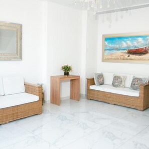 Una habitación con dos sofás de mimbre, una mesita de madera y un cuadro con una escena de playa.