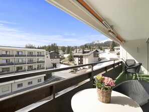 A balcony with a table and chairs, overlooking a residential area with buildings and a mountain in the background. - Nr.78 Haus Ladina Appartement/Fewo,   Nr.78 Haus Ladina IH by Interhome (Lenzerheide)