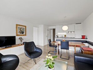 A modern living room with a flat-screen TV, leather chairs, a glass coffee table, and a dining area with a wooden table and chairs. - Nr.78 Haus Ladina Appartement/Fewo,   Nr.78 Haus Ladina IH by Interhome (Lenzerheide)