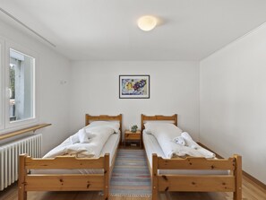 A bedroom with two wooden beds, a radiator, a window, and a framed artwork on the wall. - Nr.05 Haus Sursilvana Appartement/Fewo,   Nr.05 Haus Sursilvana IH by Interhome (Lenzerheide)