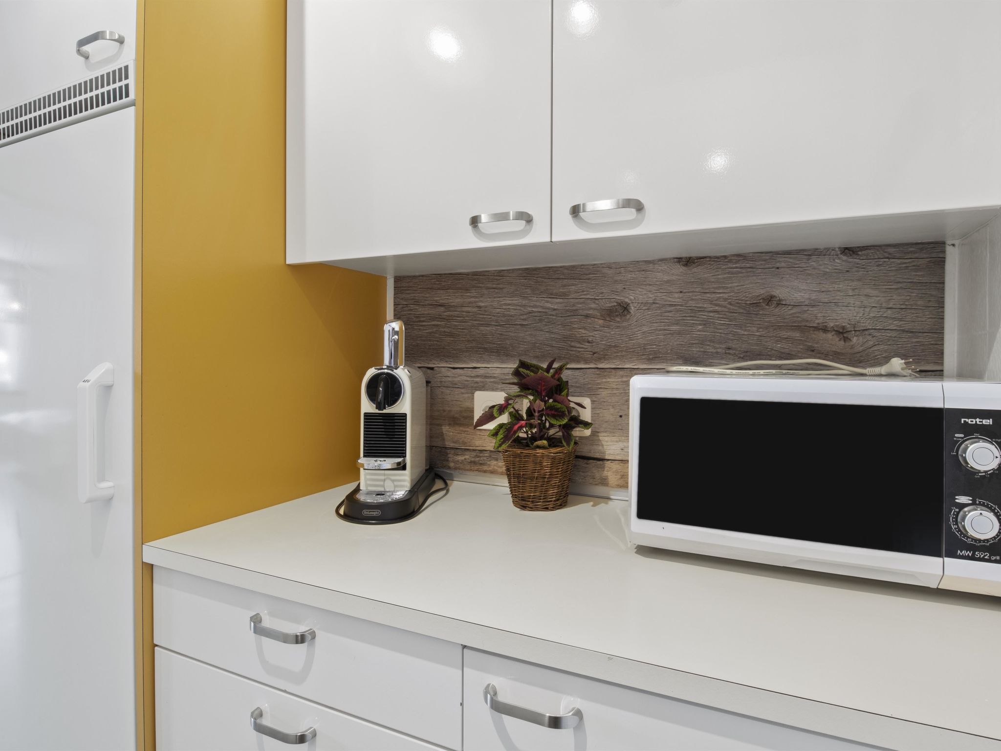 Una kitchenette equipada con microondas, tostadora y una planta en maceta.