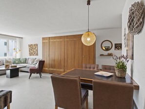 Ein modernes Wohnzimmer mit Essbereich, Holzmöbeln und einem großen Fenster.