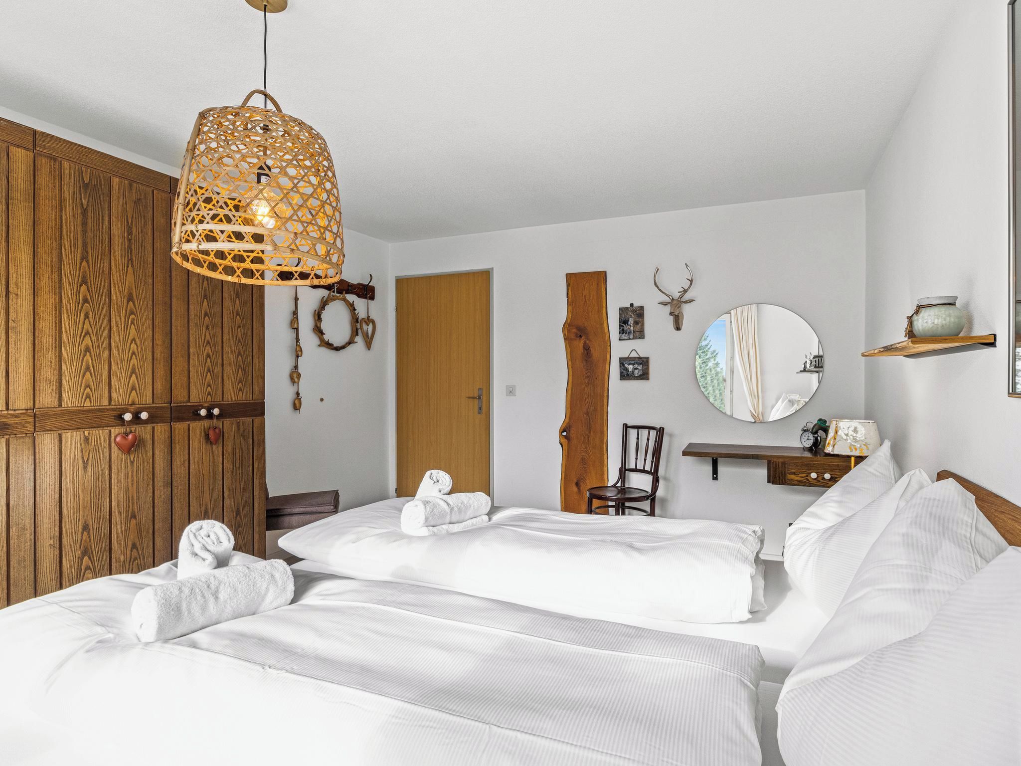 Ein Hotelzimmer mit einem Holzschrank, einem Bett mit weißer Bettwäsche, einer Hängelampe und einem an der Wand befestigten Spiegel.