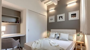 A bedroom with a bed, bedside tables, a desk, and a chair.
