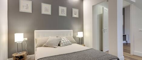 Une chambre à coucher comprenant un lit, des lampes de chevet, une table de chevet et un luminaire fixé au mur.