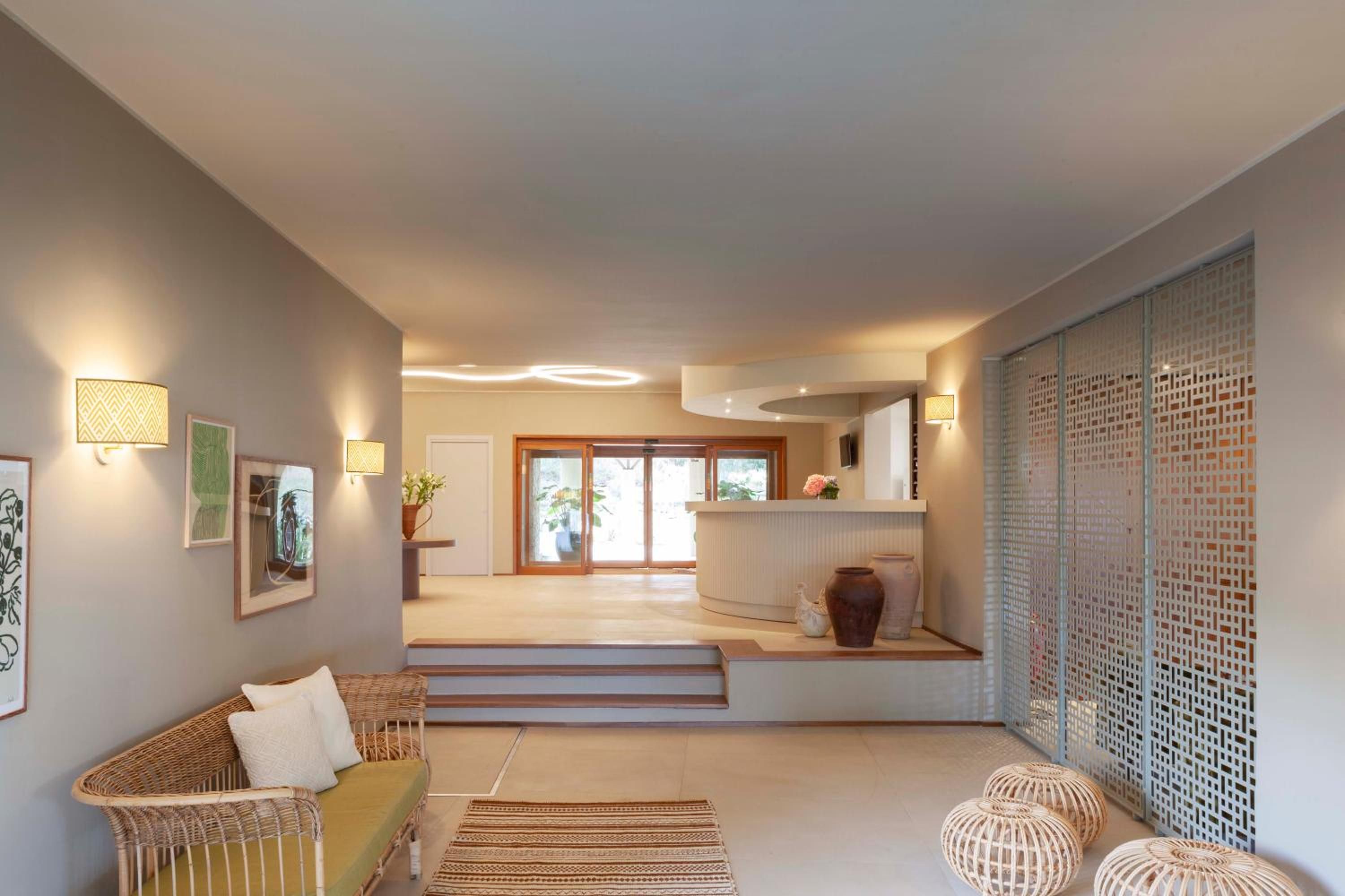 Un interno moderno con un divano, un'area pranzo e vista attraverso una porta vetrata.