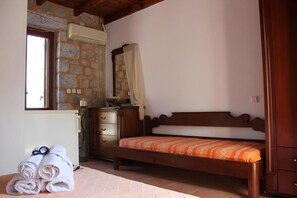 Quarto com cama de madeira, cômoda, espelho e janela.