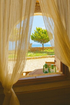 A room with a view of a tree and a stone wall through sheer curtains. - Lalloudes Seaside Accommodation (East Mani)