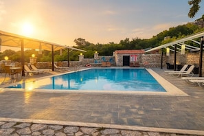 Una piscina rectangular amb gandules i una zona de seients coberta.
