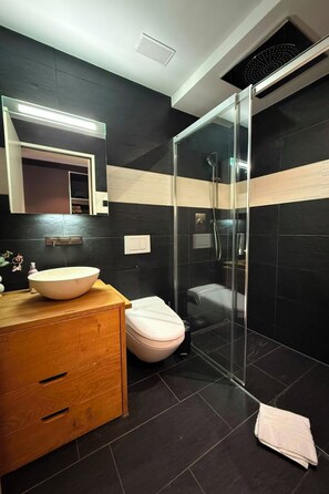 Ein modernes Badezimmer mit Duschkabine aus Glas, einem hölzernen Waschtisch mit großem Becken und einer weißen Toilette.