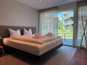 Ein modernes Hotelzimmer mit einem großen Bett, Blick ins Freie und einem Balkon.